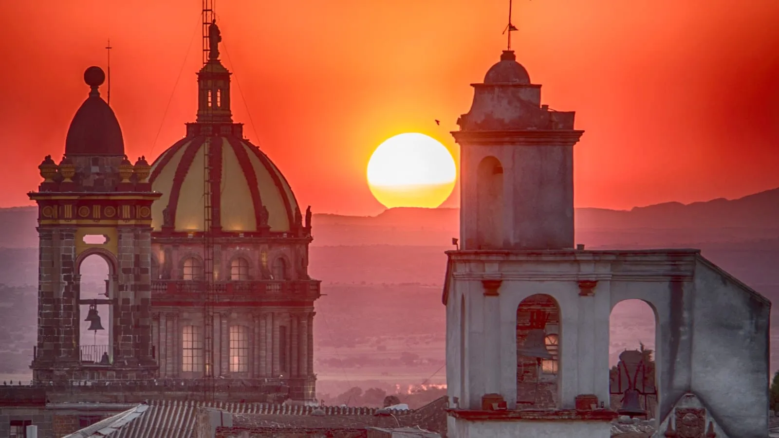 Colonial Mexican town rooftop view at golden hour with warm terracotta buildings